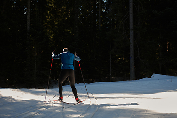 Image showing Nordic skiing or Cross-country skiing classic technique practiced by man in a beautiful panoramic trail at morning.Selective focus.