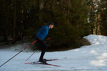 Image showing Nordic skiing or Cross-country skiing classic technique practiced by man in a beautiful panoramic trail at morning.Selective focus.