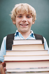 Image showing I cant wait to read them all. A cute young boy carrying a large stack of books and smiling at you.