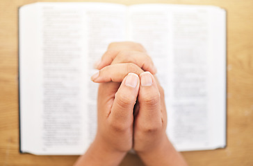 Image showing Hands, bible and desk for prayer, closeup and mindfulness for faith, religion or reading in pov. Woman, praying and study holy book for peace, mental health and worship with praise to God in top view