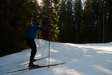 Image showing Nordic skiing or Cross-country skiing classic technique practiced by man in a beautiful panoramic trail at morning.Selective focus.