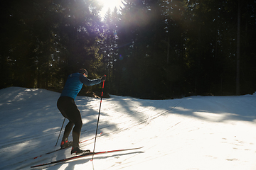 Image showing Nordic skiing or Cross-country skiing classic technique practiced by man in a beautiful panoramic trail at morning.Selective focus.