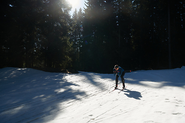 Image showing Nordic skiing or Cross-country skiing classic technique practiced by man in a beautiful panoramic trail at morning.Selective focus.