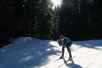 Image showing Nordic skiing or Cross-country skiing classic technique practiced by man in a beautiful panoramic trail at morning.Selective focus.