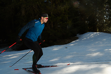 Image showing Nordic skiing or Cross-country skiing classic technique practiced by man in a beautiful panoramic trail at morning.Selective focus.