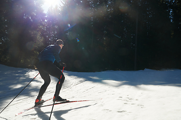 Image showing Nordic skiing or Cross-country skiing classic technique practiced by man in a beautiful panoramic trail at morning.Selective focus.