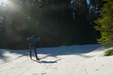 Image showing Nordic skiing or Cross-country skiing classic technique practiced by man in a beautiful panoramic trail at morning.Selective focus.