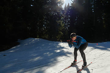 Image showing Nordic skiing or Cross-country skiing classic technique practiced by man in a beautiful panoramic trail at morning.Selective focus.