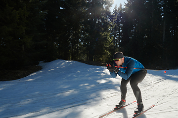 Image showing Nordic skiing or Cross-country skiing classic technique practiced by man in a beautiful panoramic trail at morning.Selective focus.