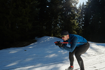 Image showing Nordic skiing or Cross-country skiing classic technique practiced by man in a beautiful panoramic trail at morning.Selective focus.