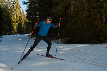 Image showing Nordic skiing or Cross-country skiing classic technique practiced by man in a beautiful panoramic trail at morning.Selective focus.