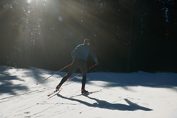 Image showing Nordic skiing or Cross-country skiing classic technique practiced by man in a beautiful panoramic trail at morning.Selective focus.