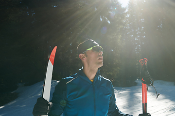 Image showing Portrait handsome male athlete with cross country skis in hands and goggles, training in snowy forest. Healthy winter lifestyle concept.