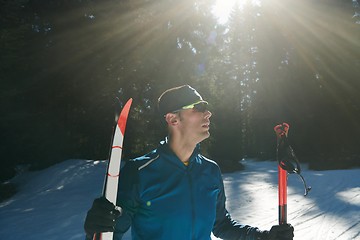 Image showing Portrait handsome male athlete with cross country skis in hands and goggles, training in snowy forest. Healthy winter lifestyle concept.