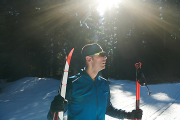 Image showing Portrait handsome male athlete with cross country skis in hands and goggles, training in snowy forest. Healthy winter lifestyle concept.