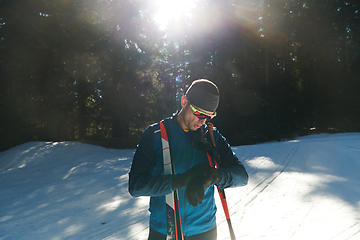 Image showing Portrait handsome male athlete with cross country skis in hands and goggles, training in snowy forest. Healthy winter lifestyle concept.