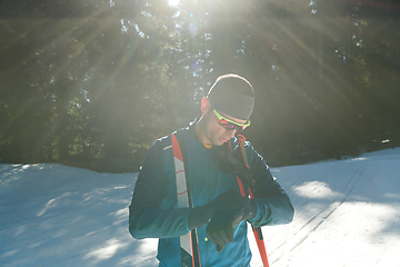 Image showing Portrait handsome male athlete with cross country skis in hands and goggles, training in snowy forest. Healthy winter lifestyle concept.