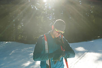 Image showing Portrait handsome male athlete with cross country skis in hands and goggles, training in snowy forest. Healthy winter lifestyle concept.