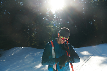 Image showing Portrait handsome male athlete with cross country skis in hands and goggles, training in snowy forest. Healthy winter lifestyle concept.