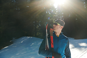 Image showing Portrait handsome male athlete with cross country skis in hands and goggles, training in snowy forest. Healthy winter lifestyle concept.