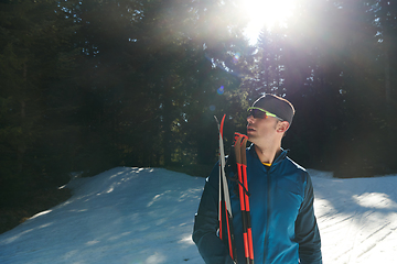 Image showing Portrait handsome male athlete with cross country skis in hands and goggles, training in snowy forest. Healthy winter lifestyle concept.