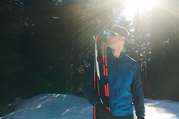 Image showing Portrait handsome male athlete with cross country skis in hands and goggles, training in snowy forest. Healthy winter lifestyle concept.