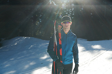 Image showing Portrait handsome male athlete with cross country skis in hands and goggles, training in snowy forest. Healthy winter lifestyle concept.