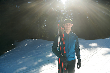 Image showing Portrait handsome male athlete with cross country skis in hands and goggles, training in snowy forest. Healthy winter lifestyle concept.