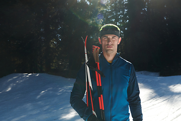 Image showing Portrait handsome male athlete with cross country skis in hands and goggles, training in snowy forest. Healthy winter lifestyle concept.