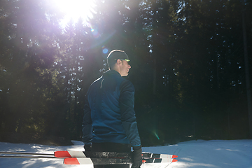 Image showing Portrait handsome male athlete with cross country skis in hands and goggles, training in snowy forest. Healthy winter lifestyle concept.