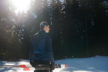 Image showing Portrait handsome male athlete with cross country skis in hands and goggles, training in snowy forest. Healthy winter lifestyle concept.