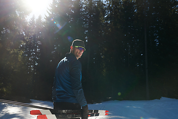 Image showing Portrait handsome male athlete with cross country skis in hands and goggles, training in snowy forest. Healthy winter lifestyle concept.