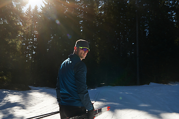 Image showing Portrait handsome male athlete with cross country skis in hands and goggles, training in snowy forest. Healthy winter lifestyle concept.