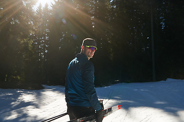 Image showing Portrait handsome male athlete with cross country skis in hands and goggles, training in snowy forest. Healthy winter lifestyle concept.