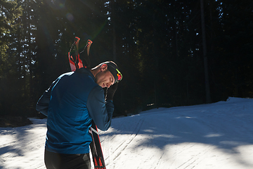 Image showing Portrait handsome male athlete with cross country skis in hands and goggles, training in snowy forest. Healthy winter lifestyle concept.