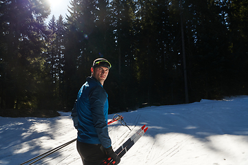 Image showing Portrait handsome male athlete with cross country skis in hands and goggles, training in snowy forest. Healthy winter lifestyle concept.