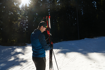 Image showing Portrait handsome male athlete with cross country skis in hands and goggles, training in snowy forest. Healthy winter lifestyle concept.