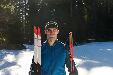 Image showing Portrait handsome male athlete with cross country skis in hands and goggles, training in snowy forest. Healthy winter lifestyle concept.