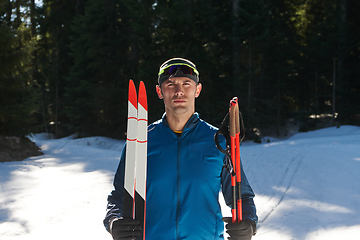 Image showing Portrait handsome male athlete with cross country skis in hands and goggles, training in snowy forest. Healthy winter lifestyle concept.