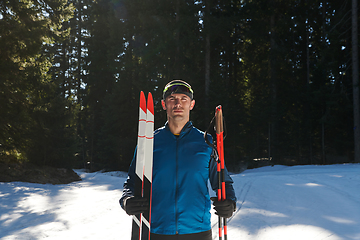 Image showing Portrait handsome male athlete with cross country skis in hands and goggles, training in snowy forest. Healthy winter lifestyle concept.