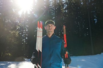 Image showing Portrait handsome male athlete with cross country skis in hands and goggles, training in snowy forest. Healthy winter lifestyle concept.