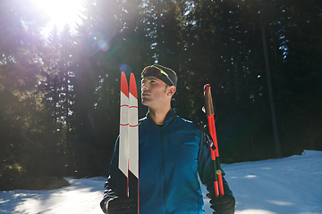 Image showing Portrait handsome male athlete with cross country skis in hands and goggles, training in snowy forest. Healthy winter lifestyle concept.