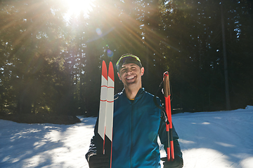 Image showing Portrait handsome male athlete with cross country skis in hands and goggles, training in snowy forest. Healthy winter lifestyle concept.