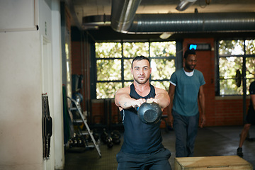 Image showing I dont need machines, I am one. Shot of a young man working out with a kettle bell at the gym.