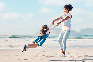 Image showing Spinning, mother and a child happy at the beach while on a family vacation, holiday or adventure. A young woman or mom and girl kid playing together while outdoor for summer fun and travel in nature