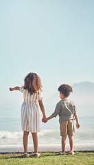 Image showing Back, holding hands and a brother with his sister on the beach, looking at a view of waves together in summer. Kids, love and pointing with a girl showing a boy the horizon on blue sky mockup space