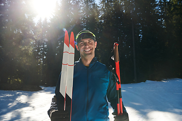 Image showing Portrait handsome male athlete with cross country skis in hands and goggles, training in snowy forest. Healthy winter lifestyle concept.