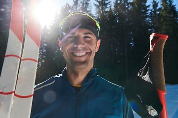 Image showing Portrait handsome male athlete with cross country skis in hands and goggles, training in snowy forest. Healthy winter lifestyle concept.