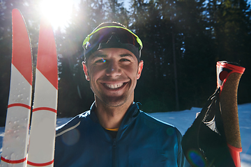 Image showing Portrait handsome male athlete with cross country skis in hands and goggles, training in snowy forest. Healthy winter lifestyle concept.