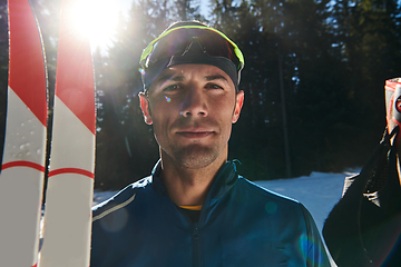 Image showing Portrait handsome male athlete with cross country skis in hands and goggles, training in snowy forest. Healthy winter lifestyle concept.